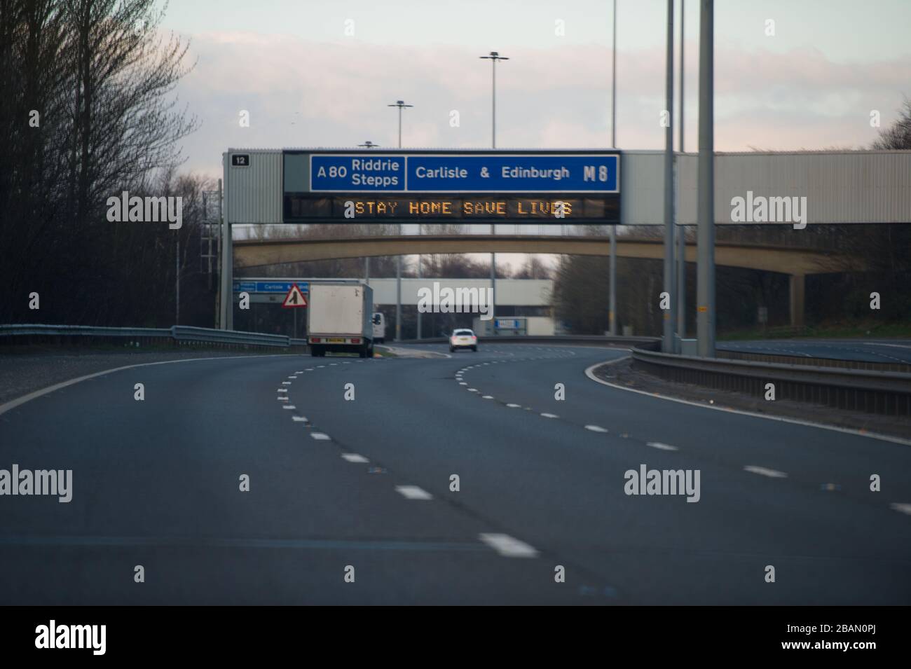 Glasgow, UK. 28th Mar, 2020. Pictured: Road signs all along the M8 and M80 motorways which read, “STAY HOME SAVE LIVES” The Coronavirus Pandemic has forced the UK Government to order a shut down of all the UK major cities and make people stay at home, which has left the motorways and all other roads free of the usual nose to tail traffic which would otherwise be there. Credit: Colin Fisher/Alamy Live News Stock Photo