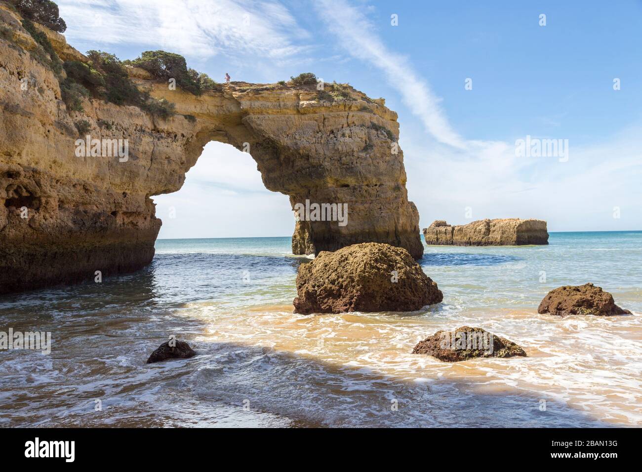 Person standing on sea arch on coast west of Alporchinhas, Algarve, Portugal Stock Photo