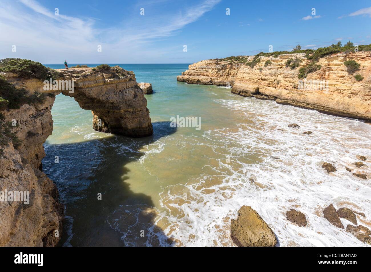 Person standing on sea arch on coast west of Alporchinhas, Algarve, Portugal Stock Photo