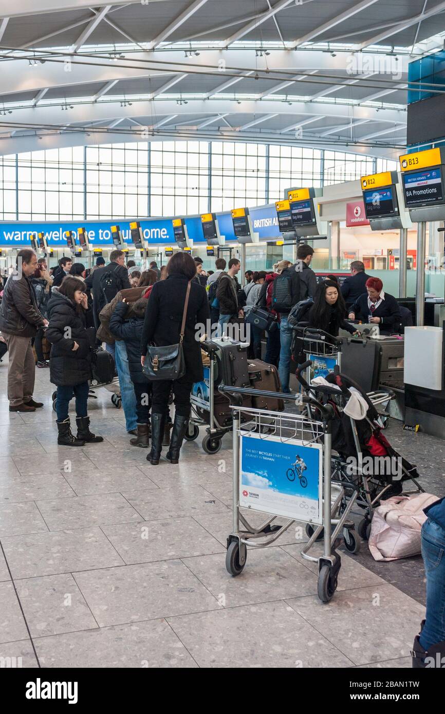 Terminal five, Heathrow Airport, London. Passengers wait in line, queuing at the baggage check-in desks. Stock Photo