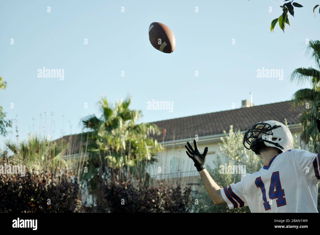 American football player in a game. Player catching an American football ball in a park. Stock Photo