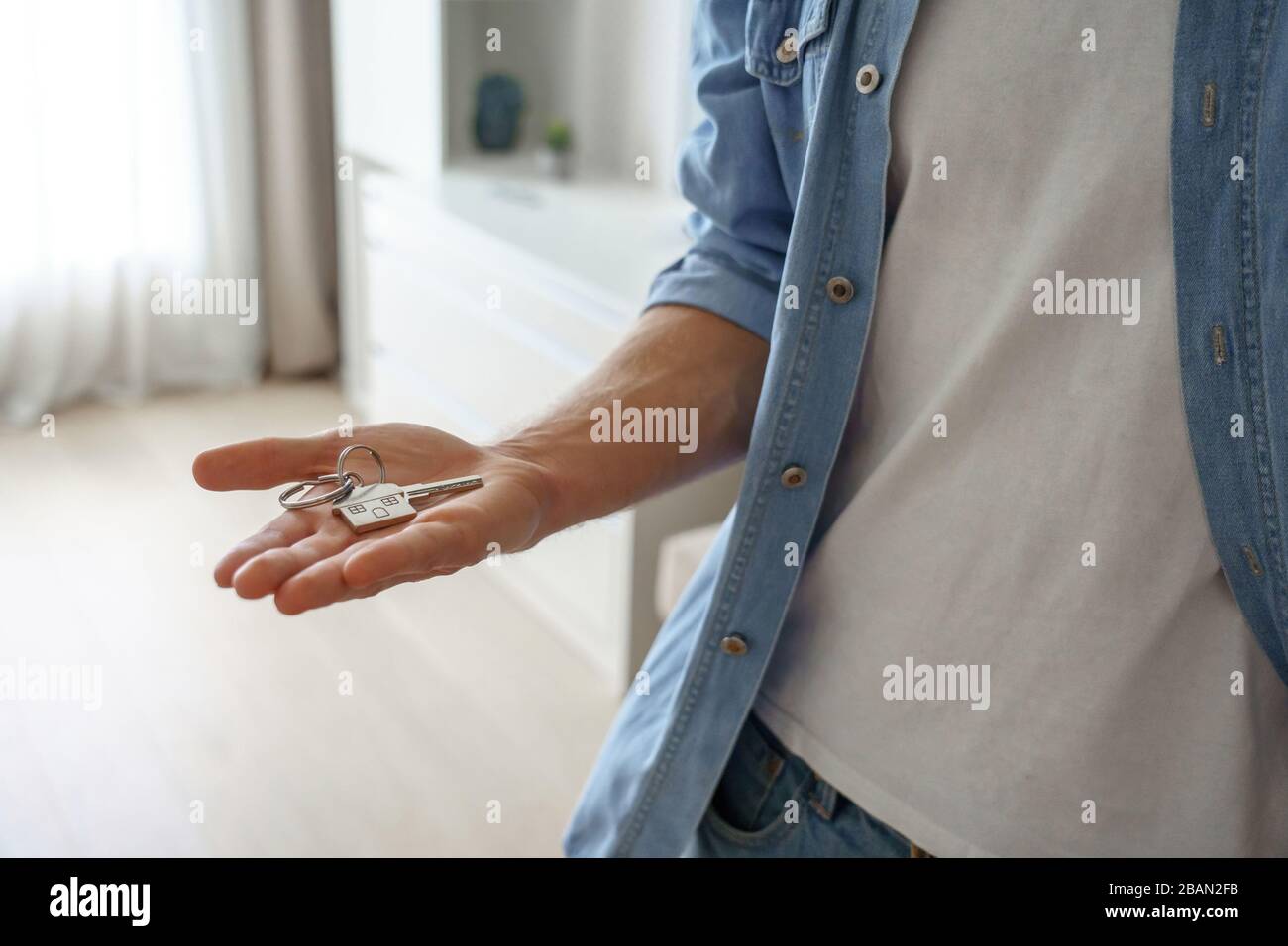 Young man renter first time home owner holding key to new apartment on hand. Stock Photo