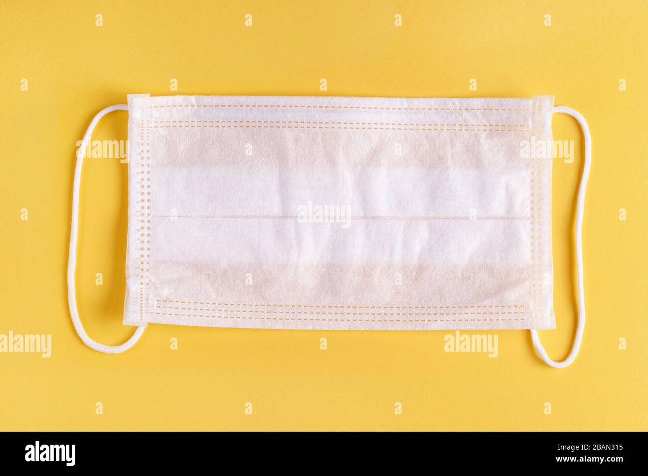 White medical mask on yellow background. Top view Stock Photo - Alamy