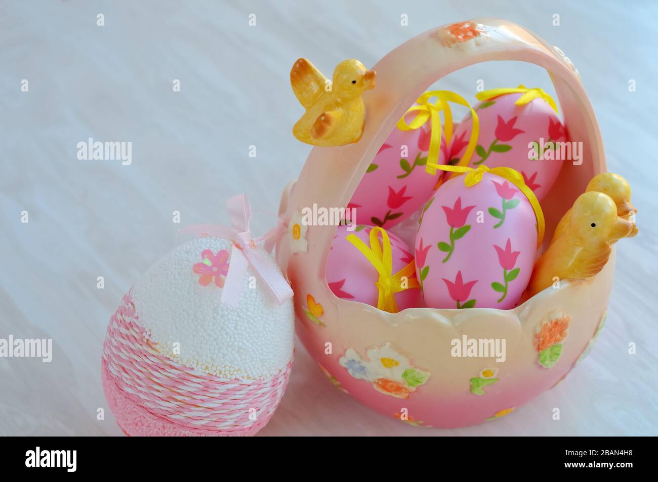 Easter ceramic basket with decorative pink eggs and chick figurines, festive home decor Stock Photo