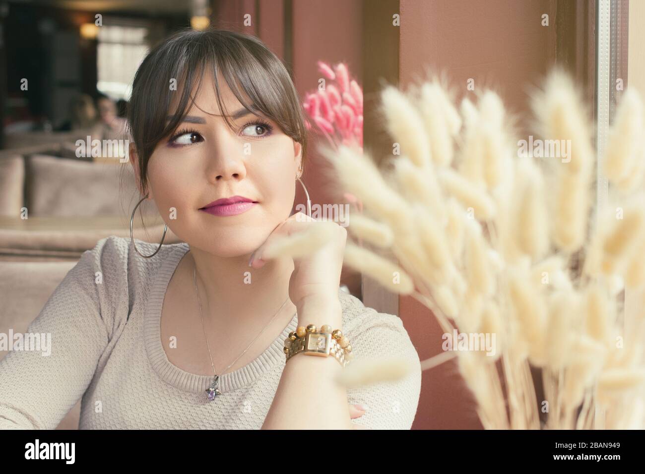 An attractive young asian woman sitting next to the window in a cafe ...