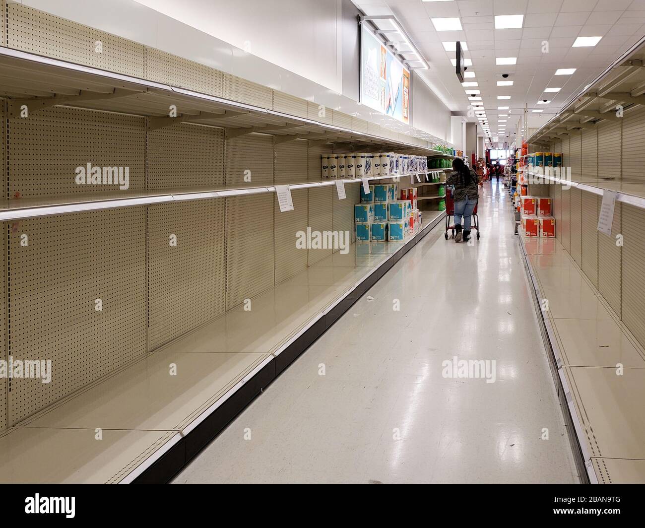 A shopper looks at the last packages of toilet paper on empty shelves early in the pandemic, March 2020, in Richmond, California. Stock Photo