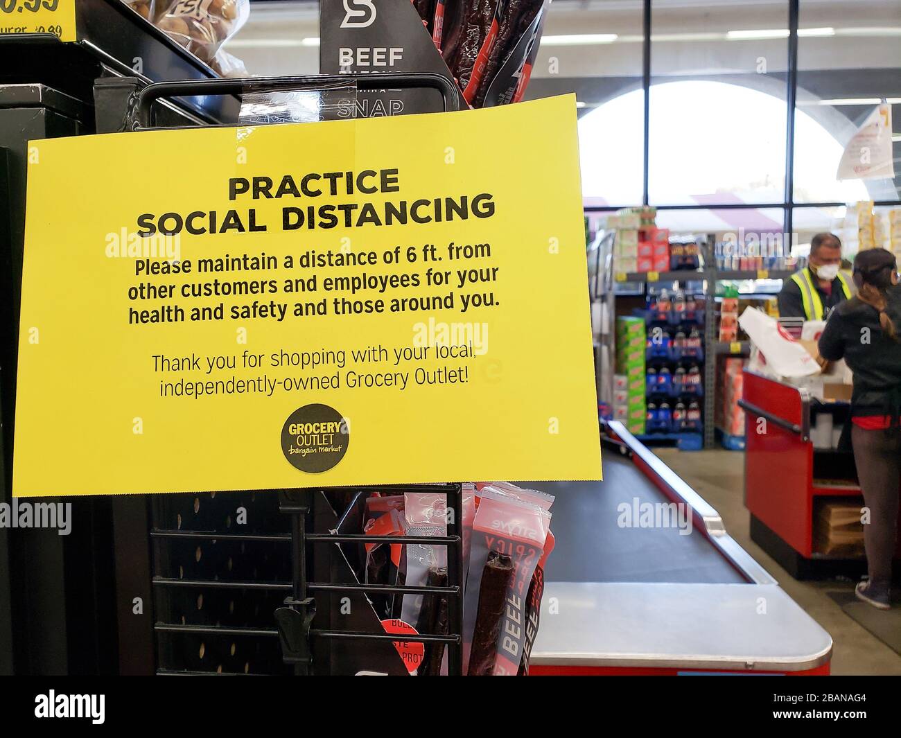 Sign at grocery store checkout advises shoppers to 'Practice social distancing' and 'Please mainiain a distance of 6 feet from other customers and employees' seen at Grocery Outlet market in El Cerrito, in the California Bay Area. March 2020. Stock Photo