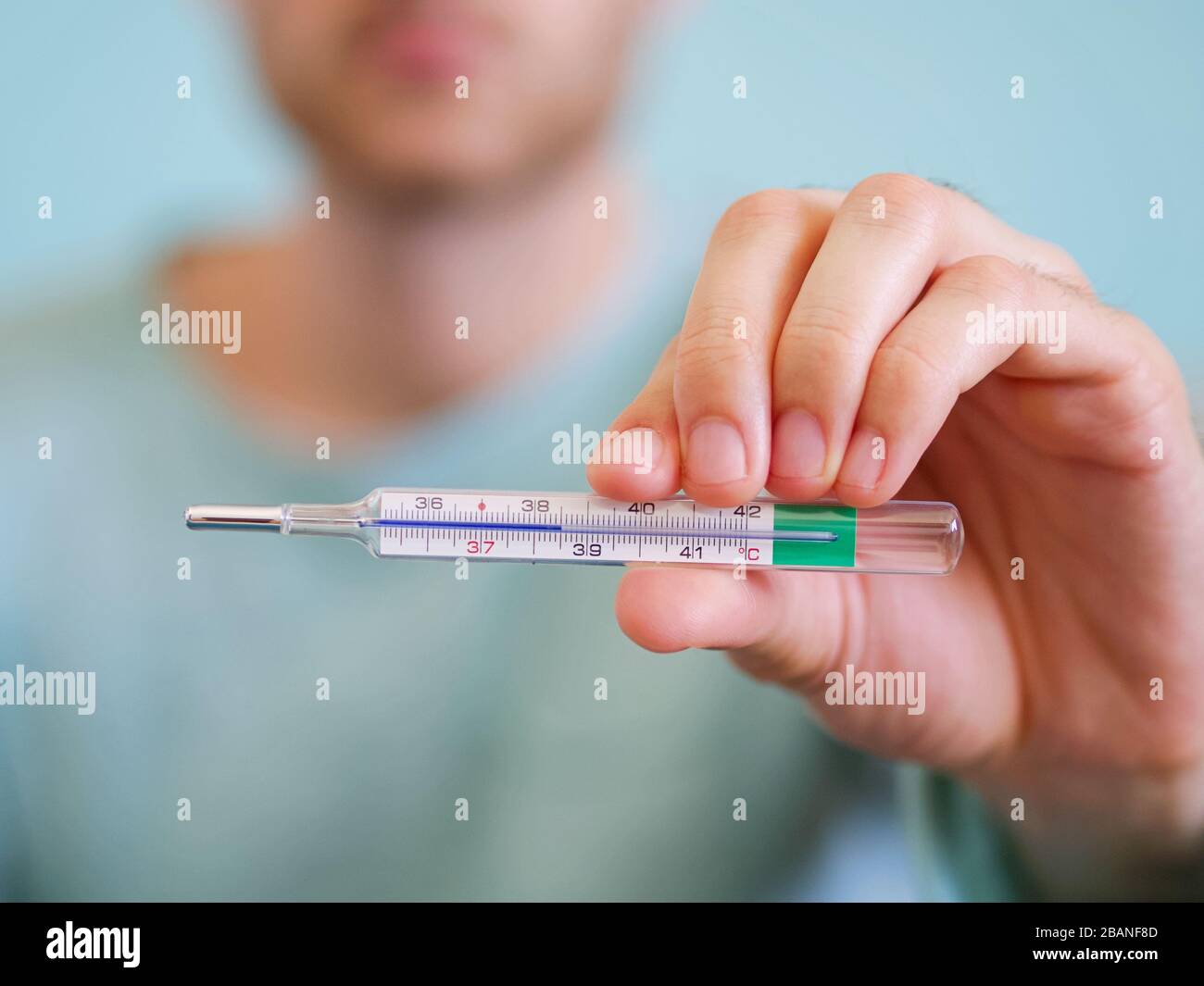 Closeup of a man holding a thermometer for measuring body temperature degrees Celsius at 38,5 background. Stock Photo