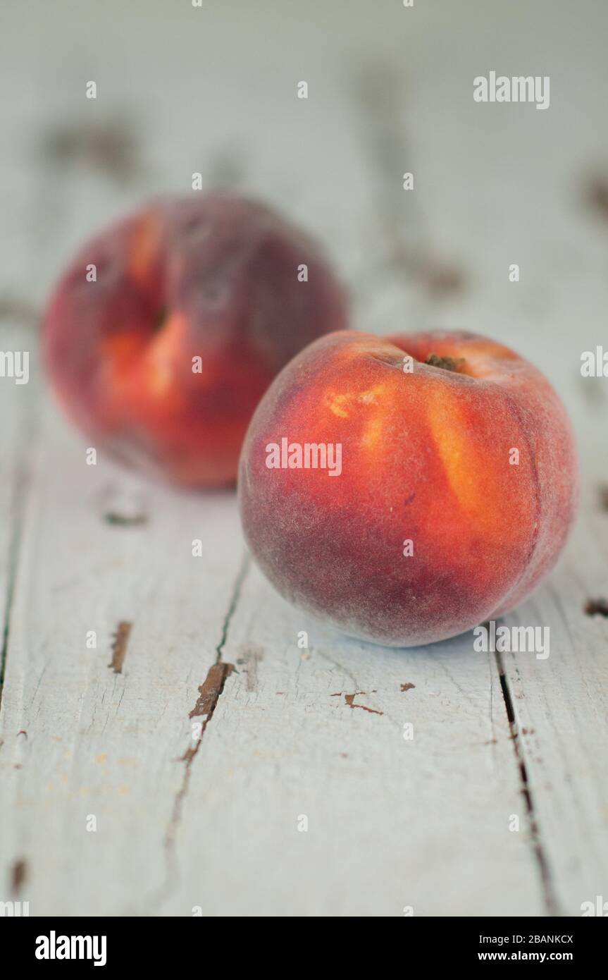 Two fresh, ripe peaches on a white wooden background Stock Photo - Alamy