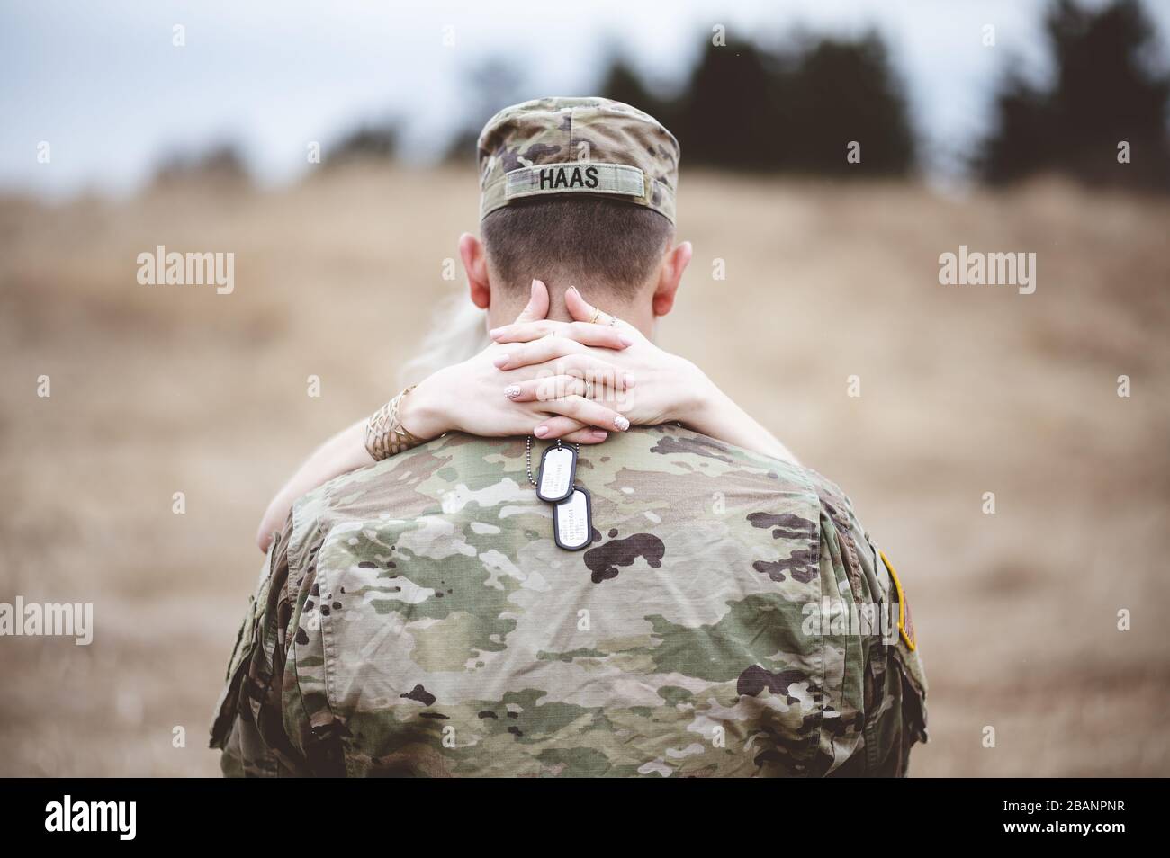Shallow focus shot of the back of an American soldier with female arms wrapped around his back Stock Photo