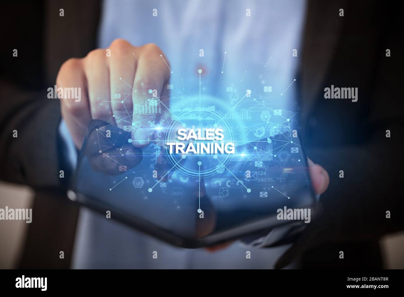Businessman holding a foldable smartphone with SALES TRAINING inscription, new business concept Stock Photo