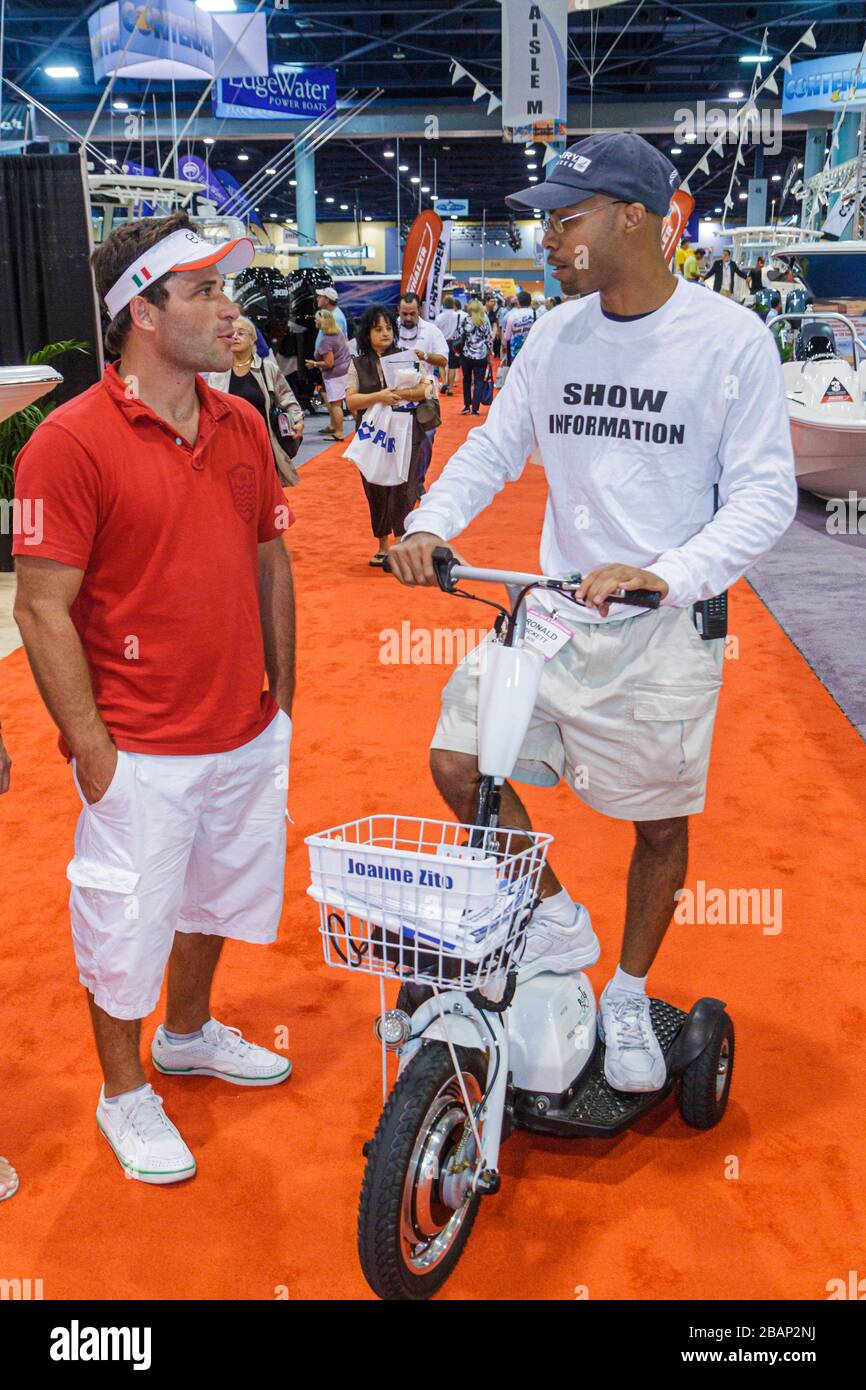 Miami Beach Florida,Miami Beach Convention Center,Miami International Boat Show,information guide,Black man men male adult adults,scooter,answers ques Stock Photo