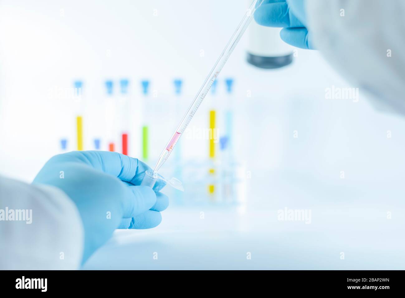 Hands in gloves using a graduated glass pipette Stock Photo