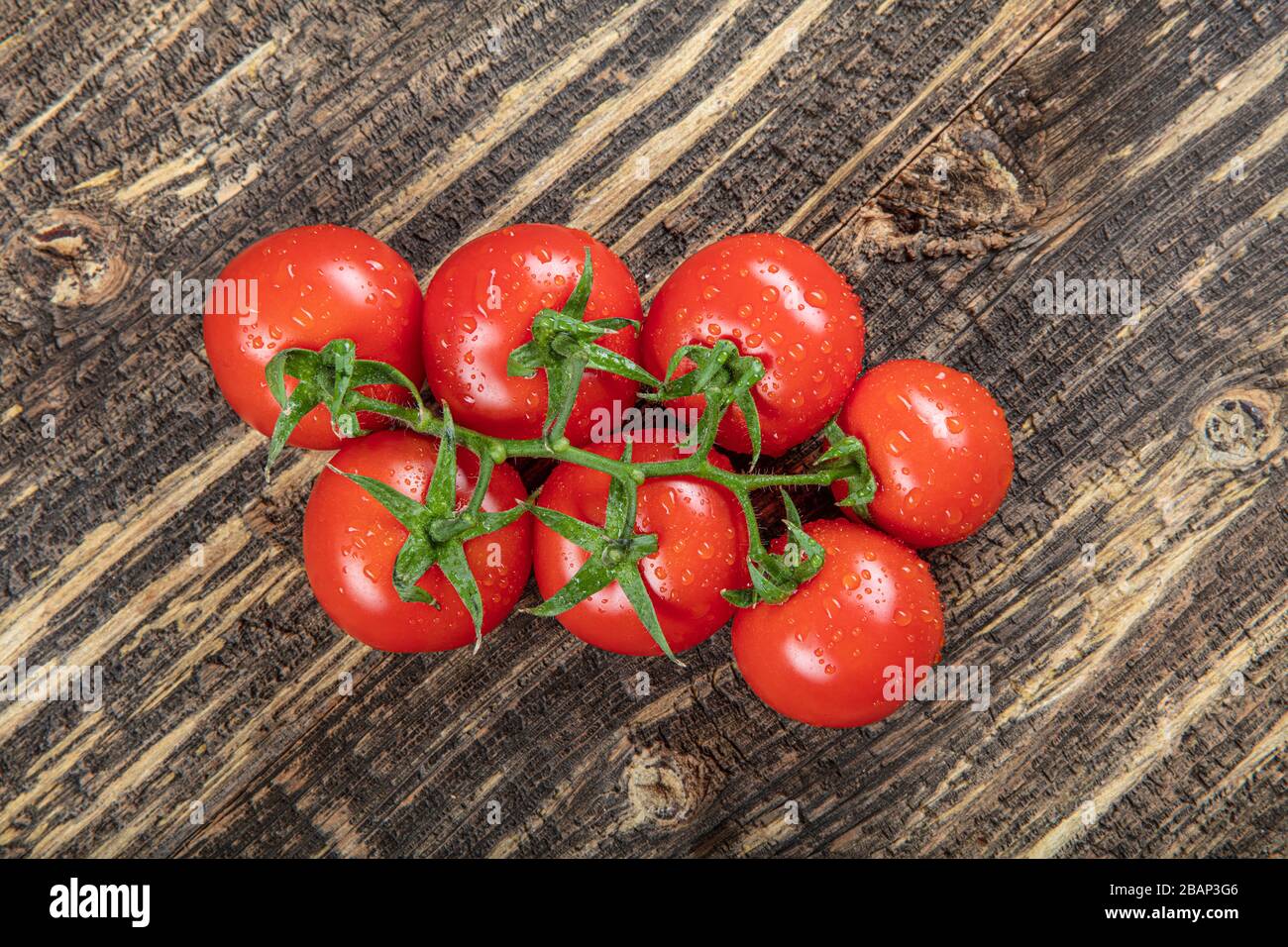 Tomatoes on the vine on rustic wooden background Stock Photo - Alamy