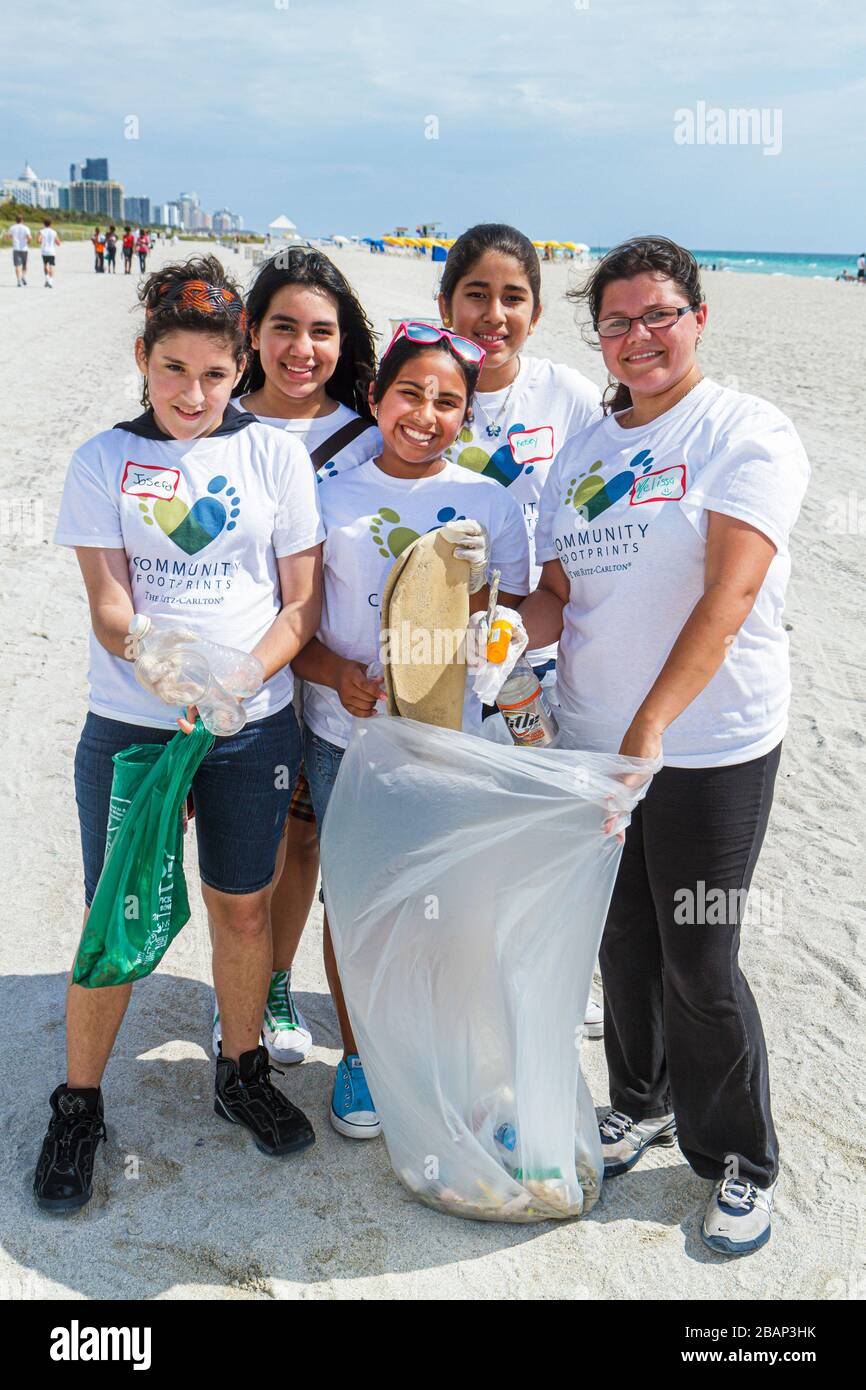 Miami Beach Florida,volunteers Hispanic boys male girls female,picking gathering collecting garbage bag group friends smiling teen teens teenagers Stock Photo