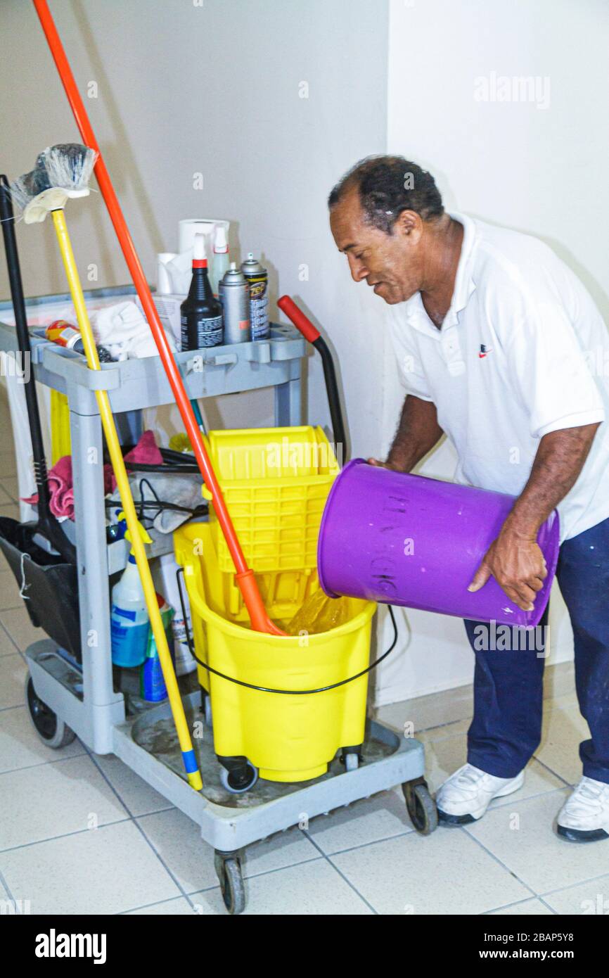 Miami Beach Florida,Presidential Condominiums,custodian working,employee worker,Hispanic man male janitor into mop bucket pouring water manual labor Stock Photo