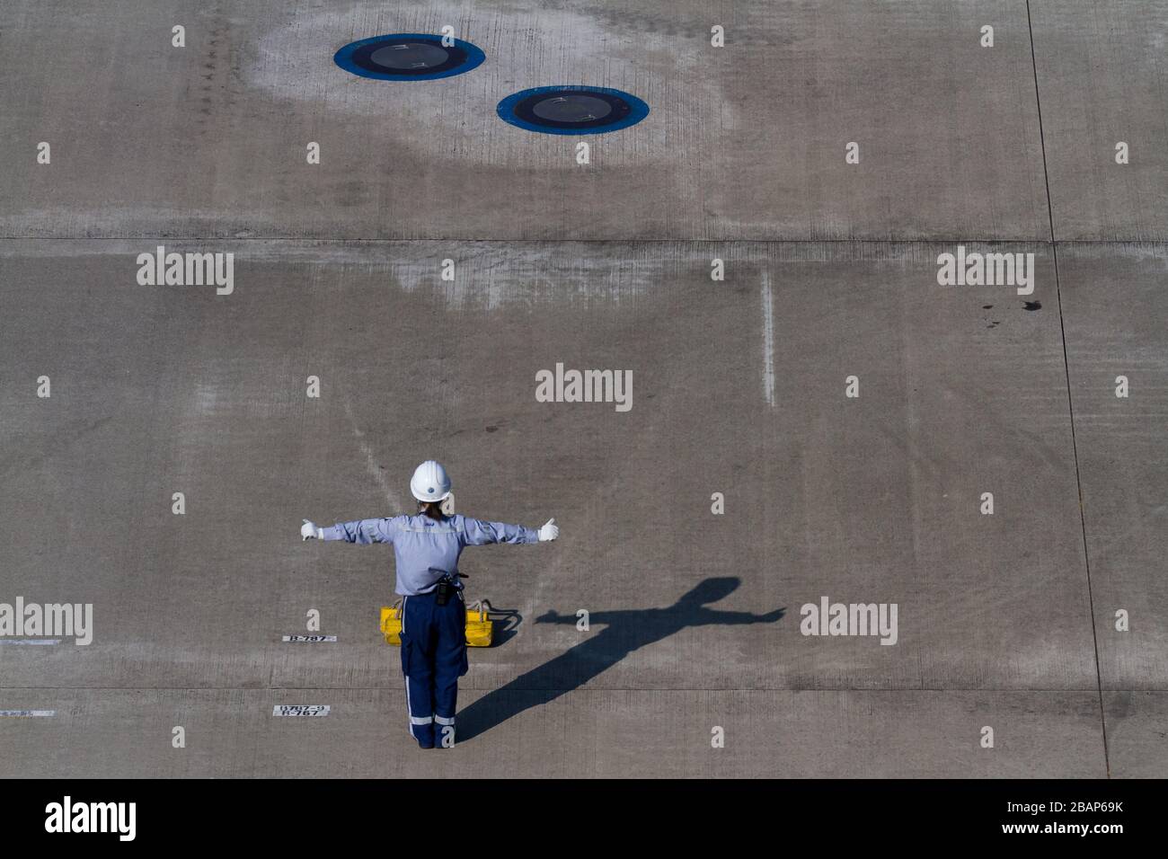 A woman ground crew worker directing an airliner at Haneda Airport, Tokyo, Japan. Stock Photo