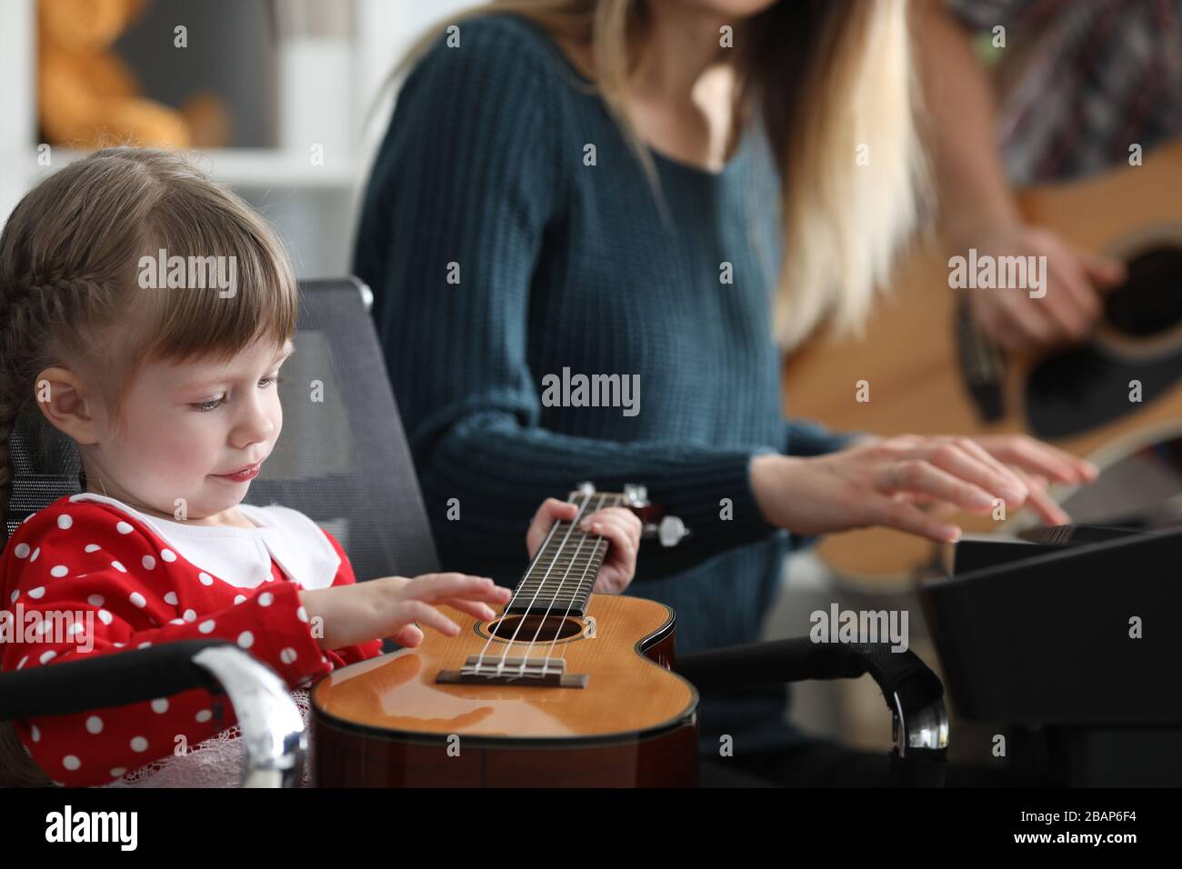 Parents teach baby to play ukulele music together Stock Photo Alamy