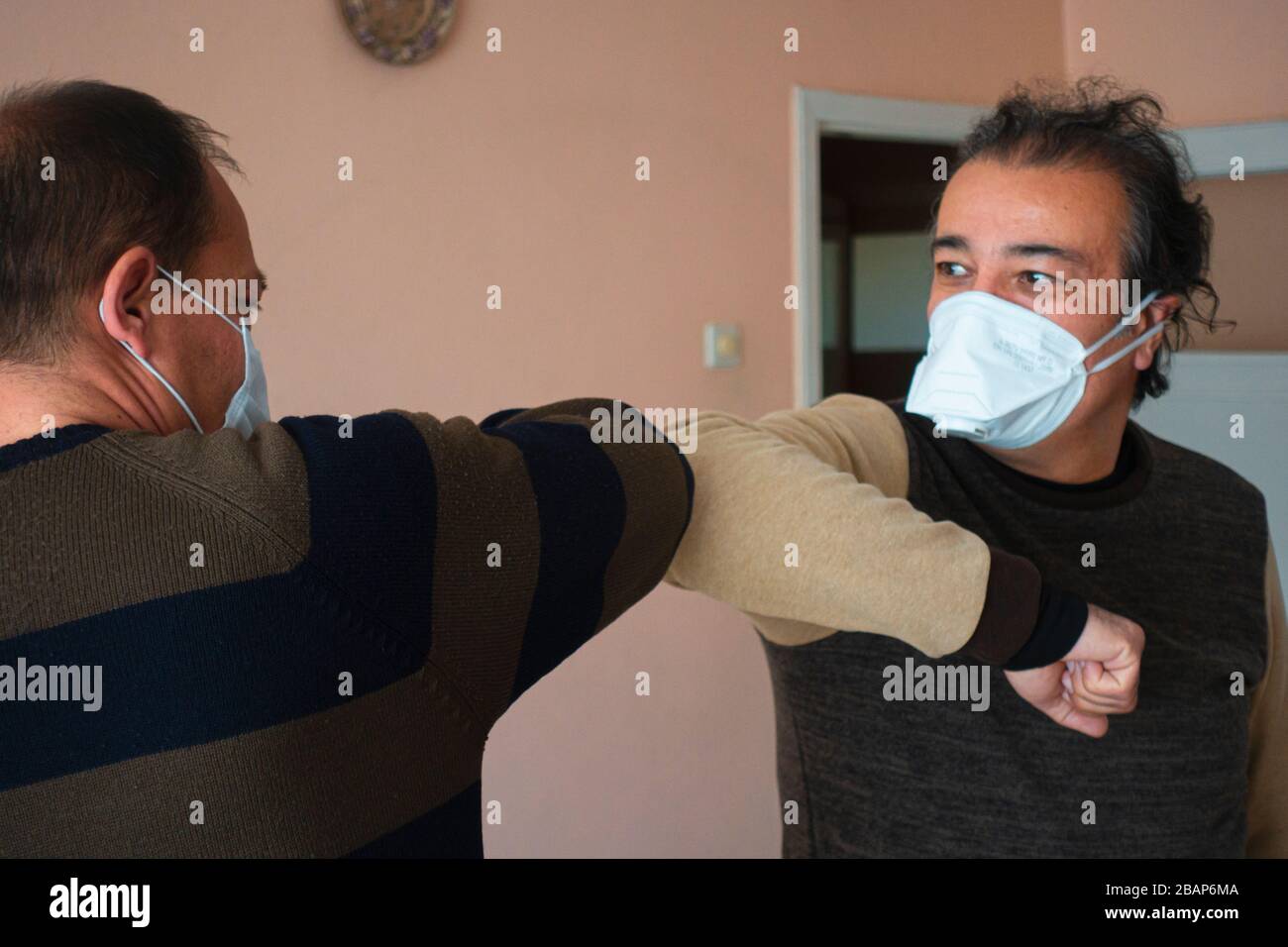 Two Turkish senior men with masks elbow bumping because of coronavirus Stock Photo