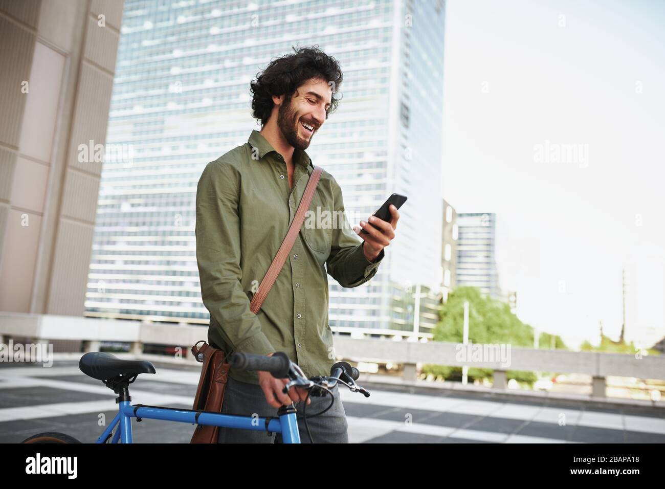 Handsome young man with beard and cycle using smartphone to read text message Stock Photo