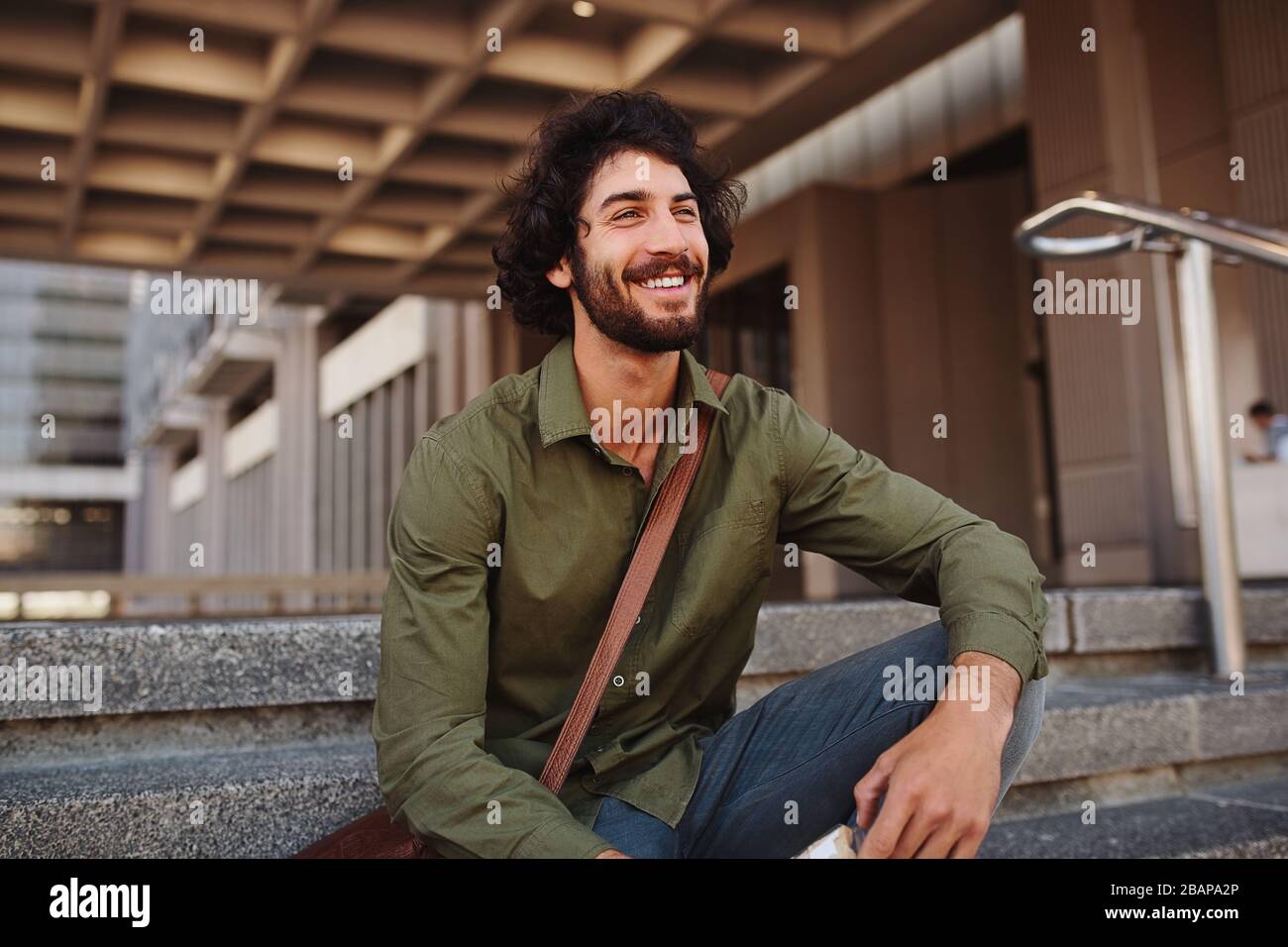 Handsome young man sitting on stairs while looking away Stock Photo