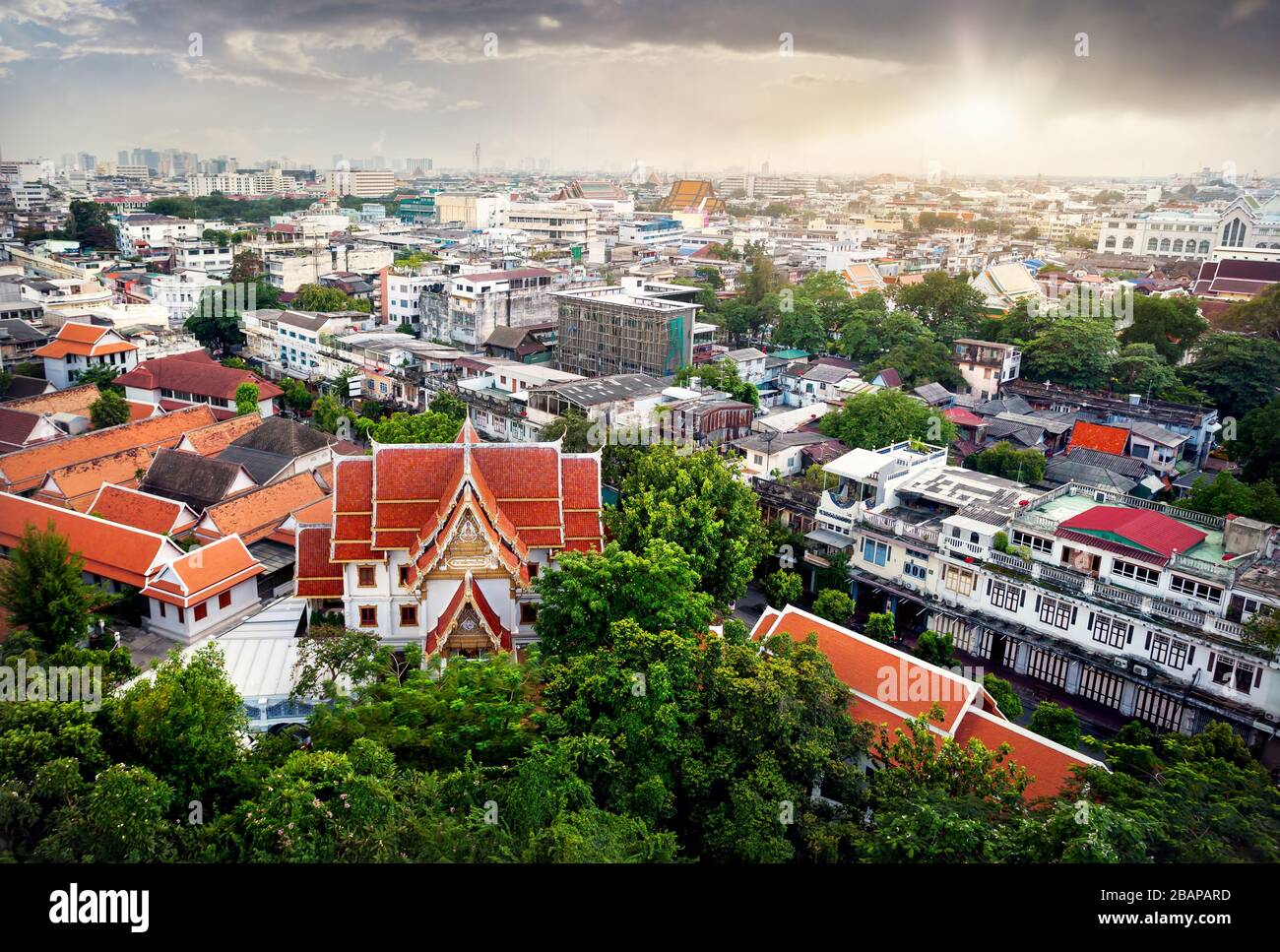 Red pagoda temple and Bangkok city view with skyscrapers business district from Golden Mountain Pagoda Wat Saket at sunset sky background Stock Photo