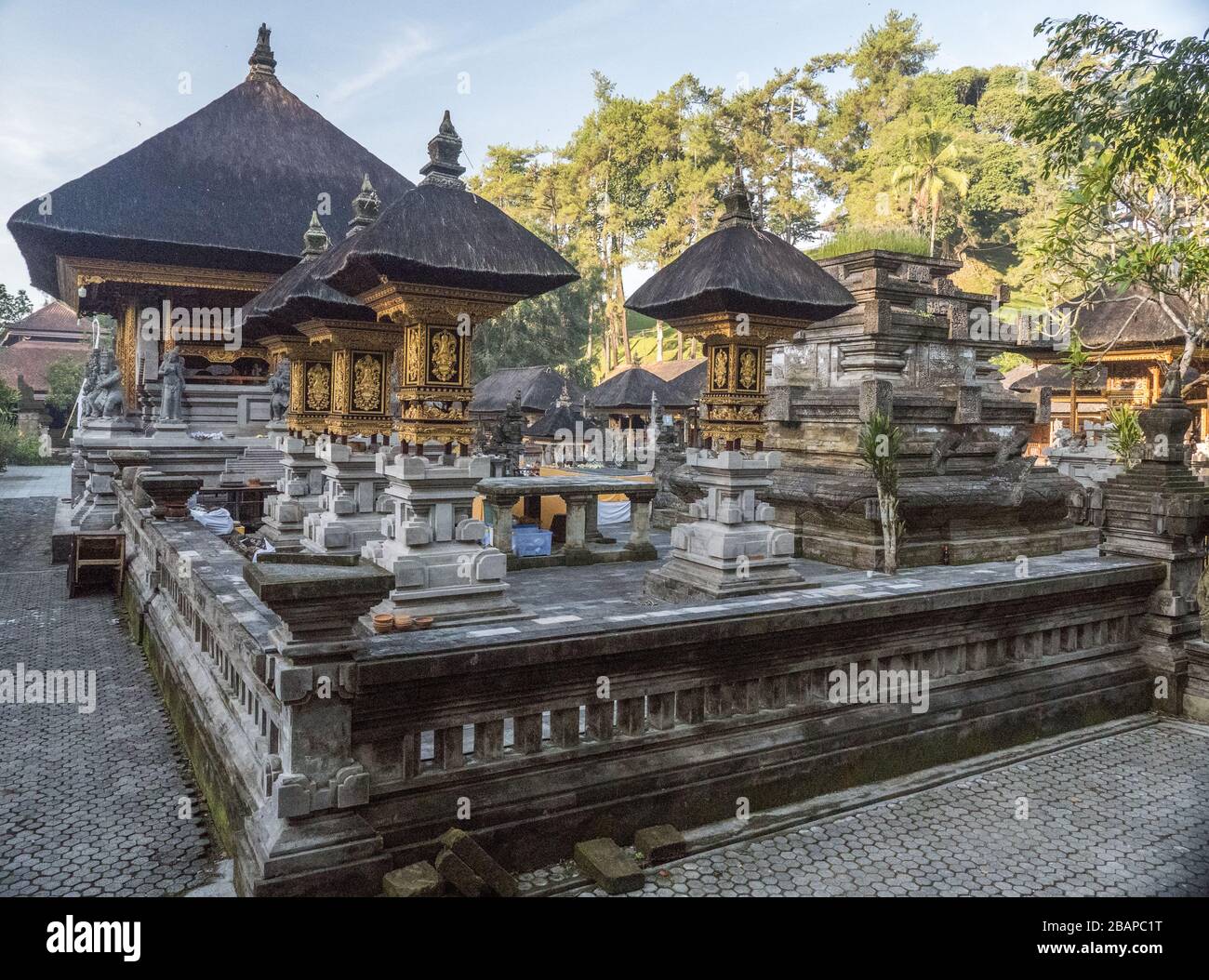Inner courtyard of Holy Water Temple in Bali Indonesia with golden temple structures and black roofs in early morning light with no people. Stock Photo