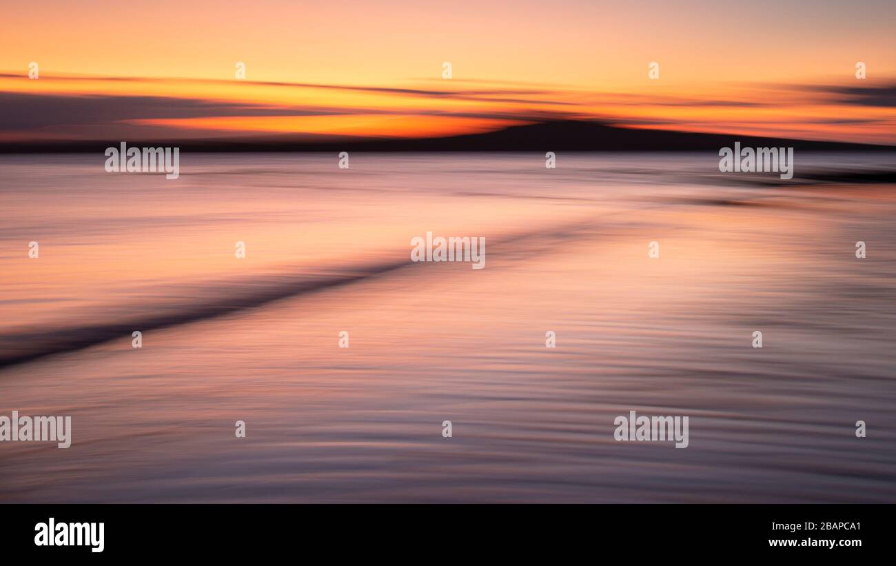 A tranquil seascape of the Milford beach at sunrise. Image made using intentional camera movement technique. Stock Photo