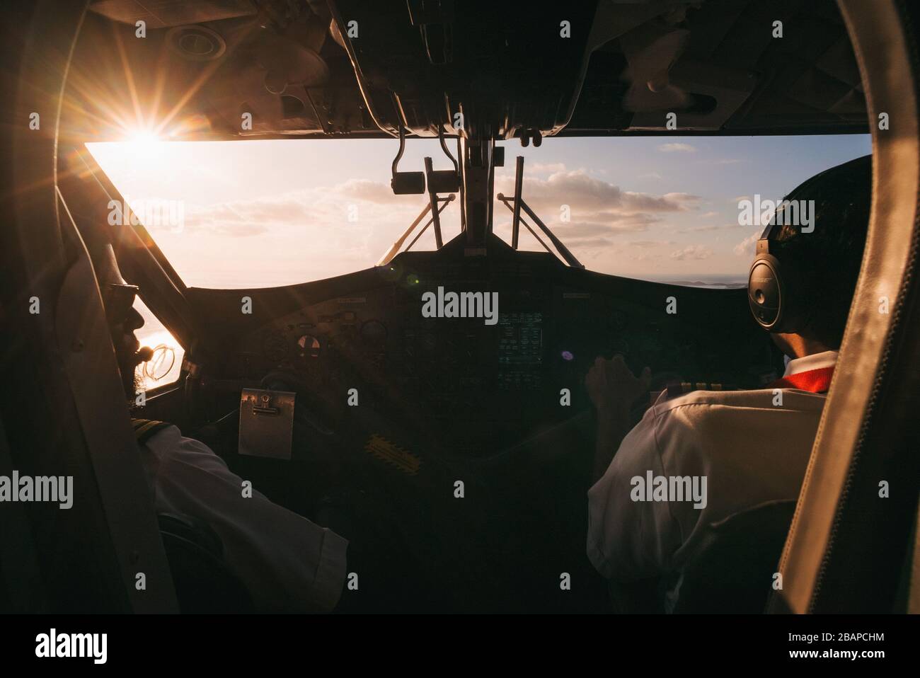 The setting sun pierces the cockpit window aboard a Winair DHC6 Twin Otter, on an island hopping flight Stock Photo