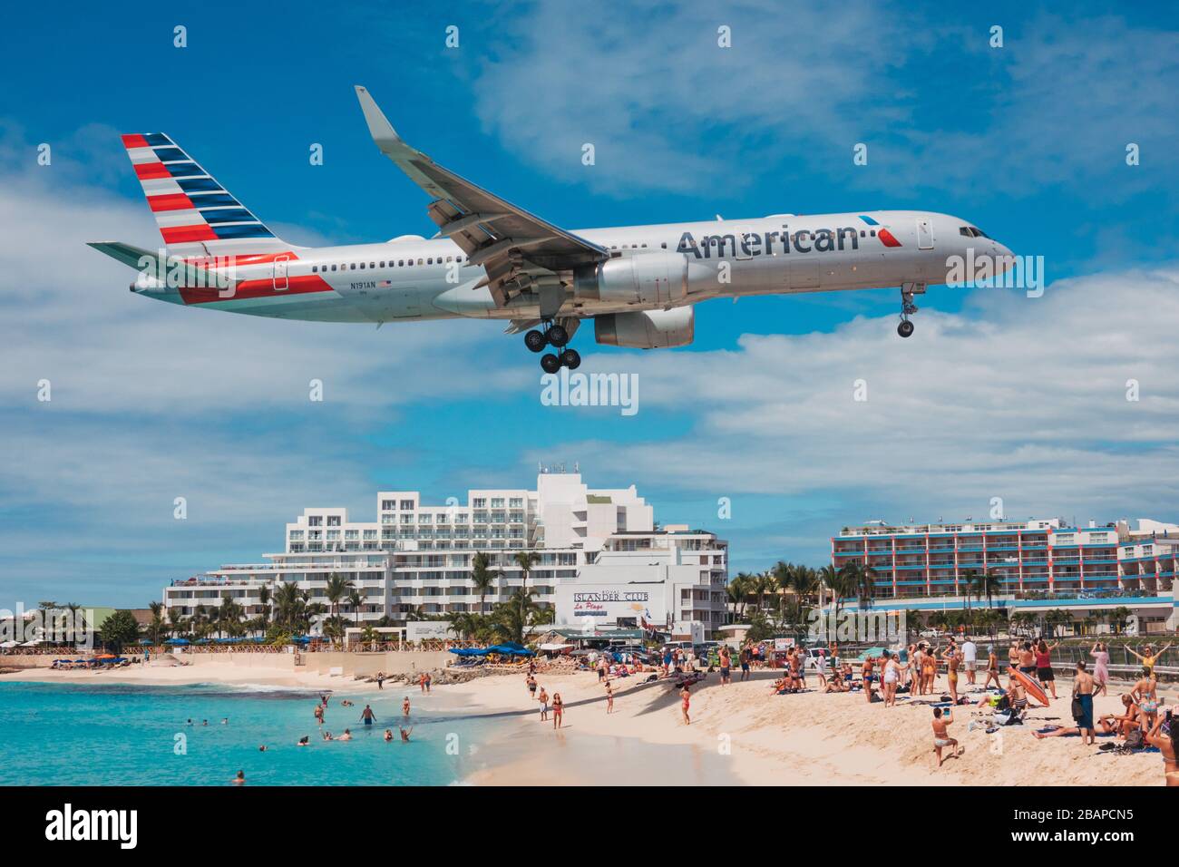 An American Airlines Boeing 757 flies over tourists sunbathing and swimming on Maho Beach, St. Maarten Stock Photo