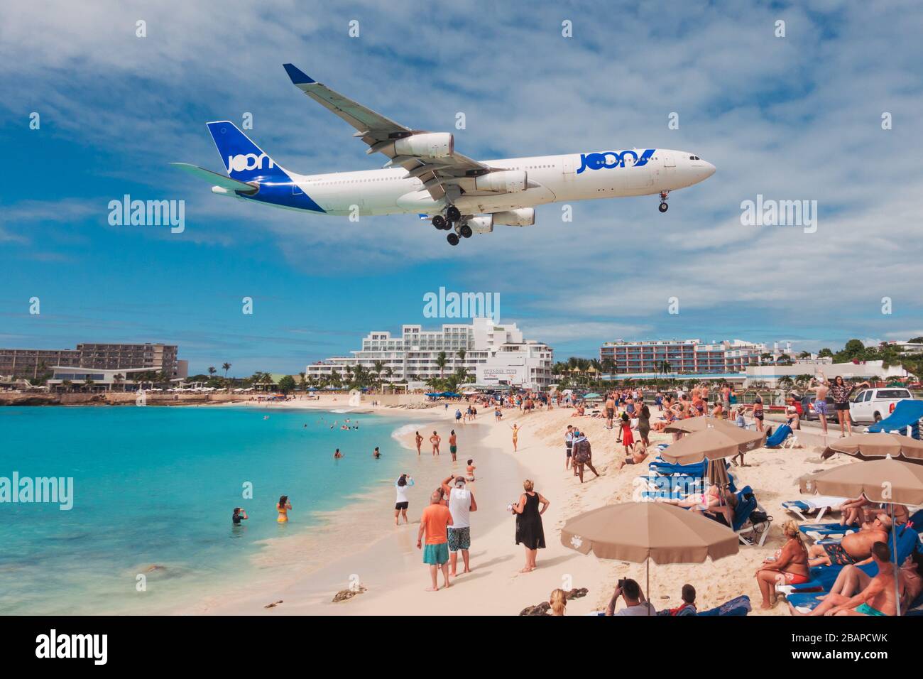 An Air France JOON Airbus A340-300 sails over tourists on Maho Beach, St. Maarten Stock Photo