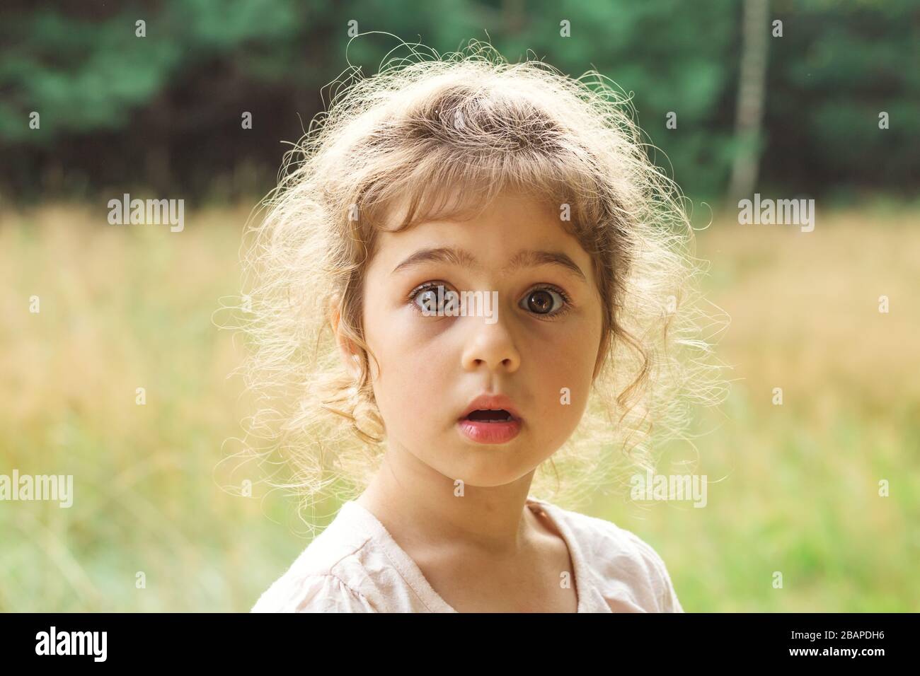 Close up Portrait of beautiful little Girl  surprised with something at summer day Stock Photo