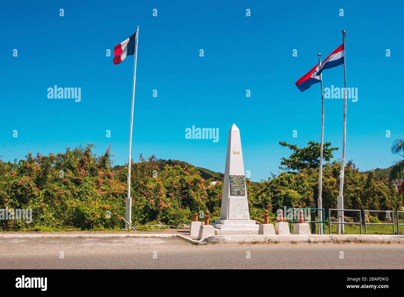 Flags fly at the Monument to Unity and Friendship at the border between the French and Dutch sides of the Caribbean island of St. Martin / St. Maarten Stock Photo