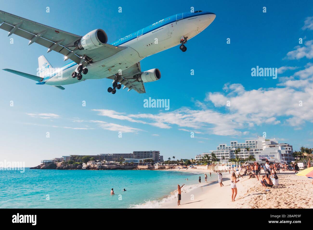 An Airbus A330-200 series operated by KLM Royal Dutch Airlines flies over tourists on Maho Beach, St. Maarten, on approach to Princess Juliana Airport Stock Photo