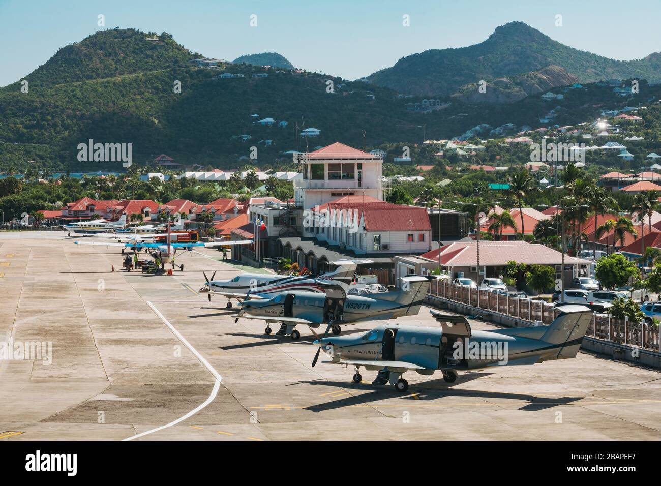 A row of aircraft parked in front of the small terminal building at Saint Barthélemy Airport Stock Photo
