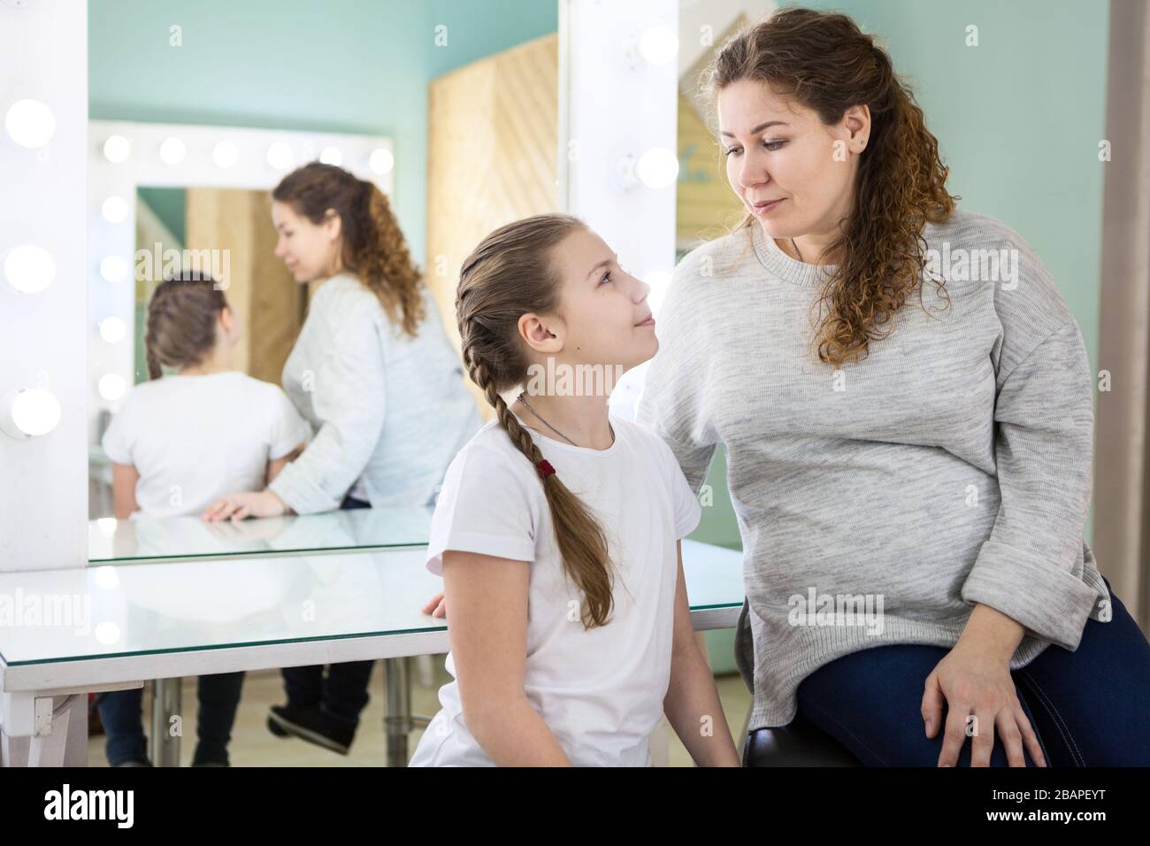 Mother brought her daughter to the casting of actors, waiting their turn in dressing room, looking each other Stock Photo
