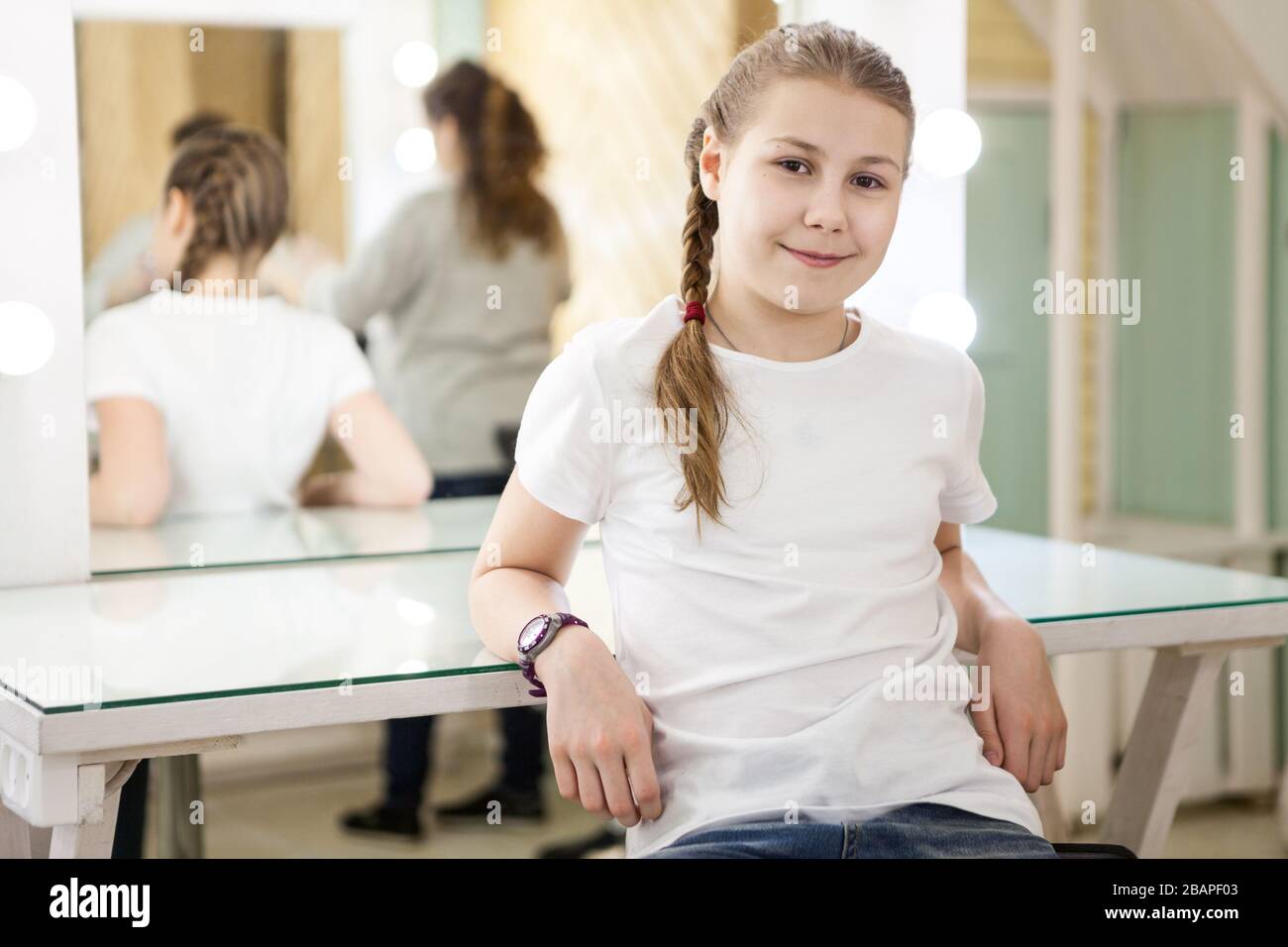 Relaxed teen girl a model sitting in dressing room after casting, mother ready to leave the studio room Stock Photo