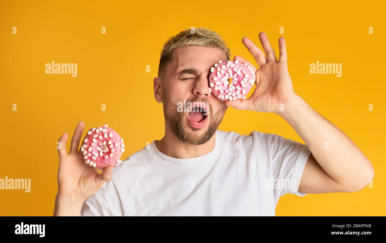 Cheerful guy looking in hole donut, panorama Stock Photo