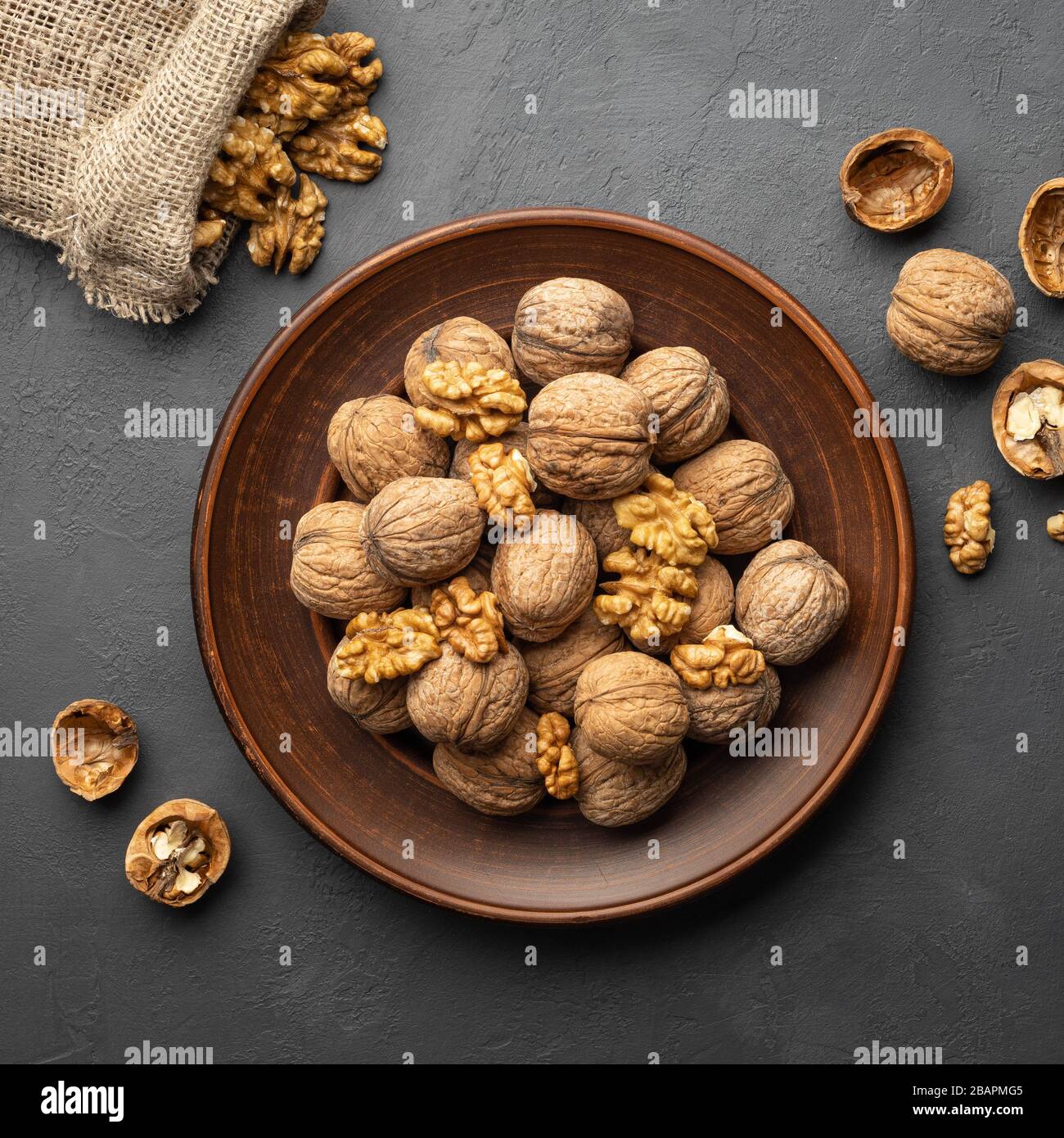 Nuts. Walnut kernels and whole walnuts on dark stone table. Top view, flat lay. Stock Photo