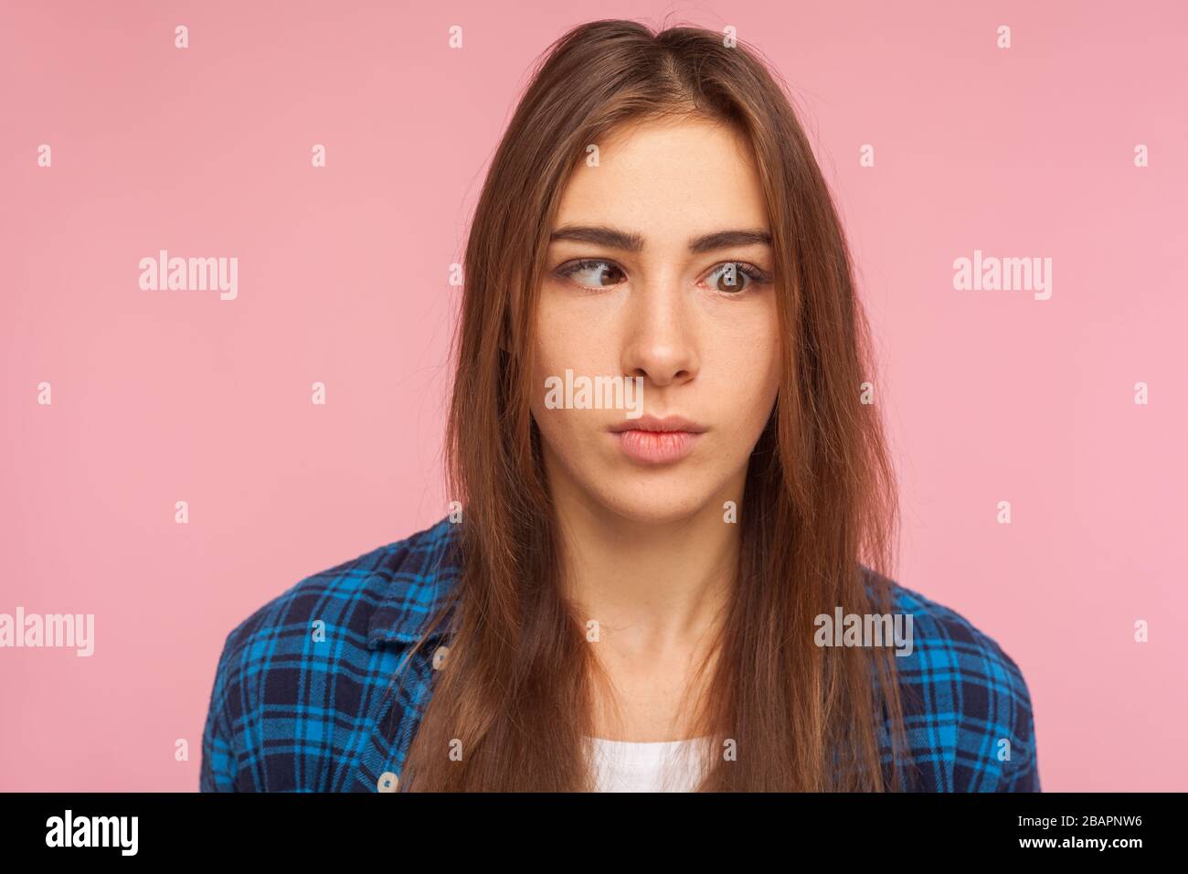 Closeup portrait of positive brunette girl in checkered shirt looking with one crossed eye, making silly awkward face, having fun, childish behavior. Stock Photo