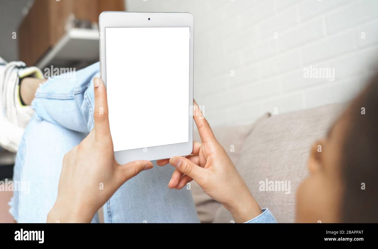 Young african woman using digital tablet looking at mock up white screen. Stock Photo
