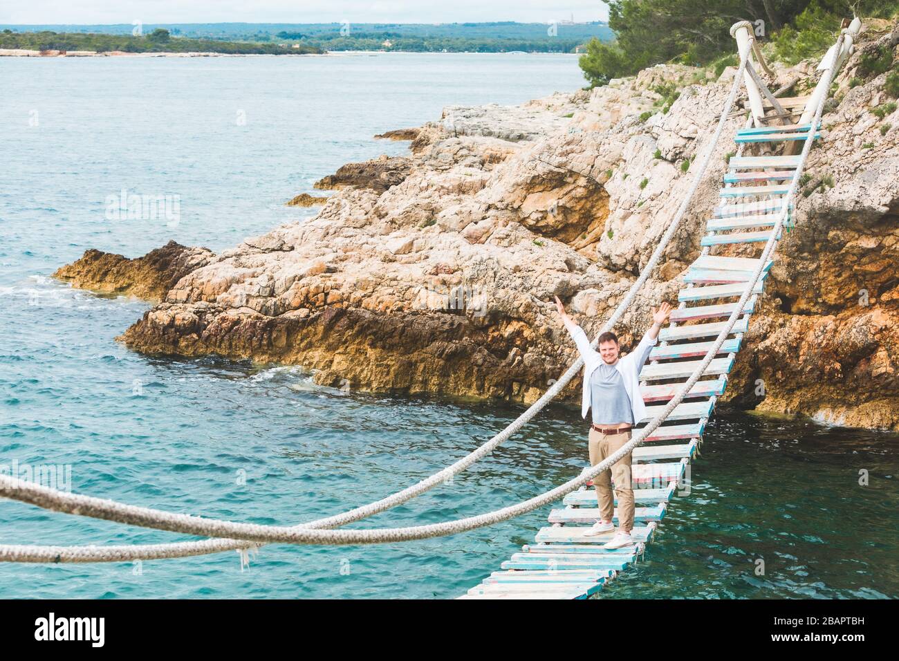 man walking by suspension bridge cross adriatic sea Stock Photo - Alamy