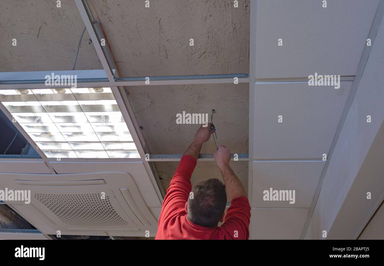 Worker repairing board ceiling with gypsum. In the classroom Stock Photo