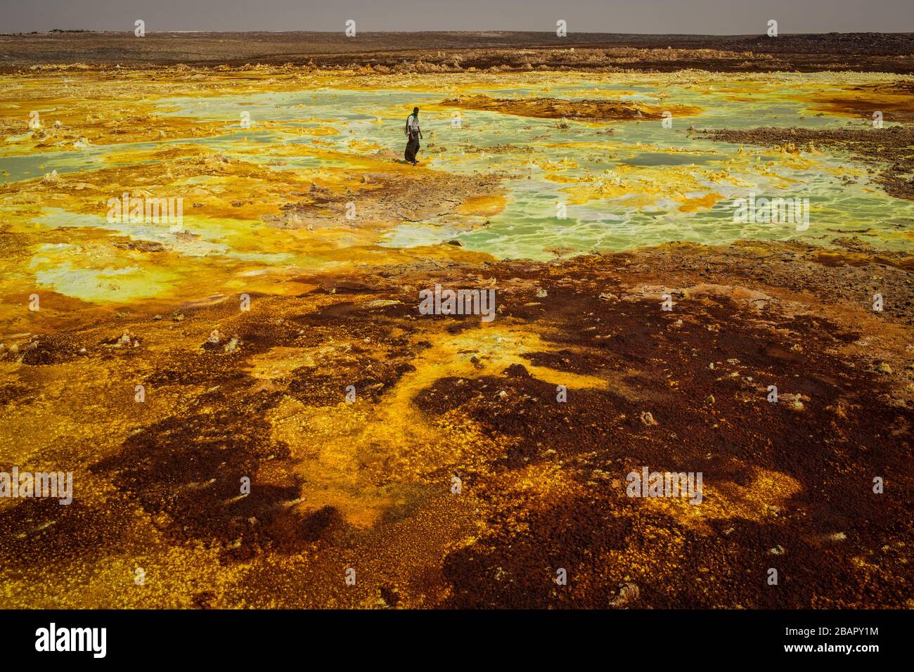 A man walks on sulphur and mineral salt formations near Dallol in the Danakil Depression, northern Ethiopia April 22, 2013. Stock Photo