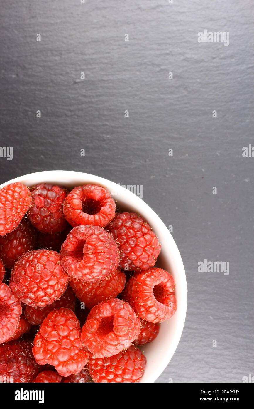 fresh red raspberry fruits in a small white bowl Stock Photo