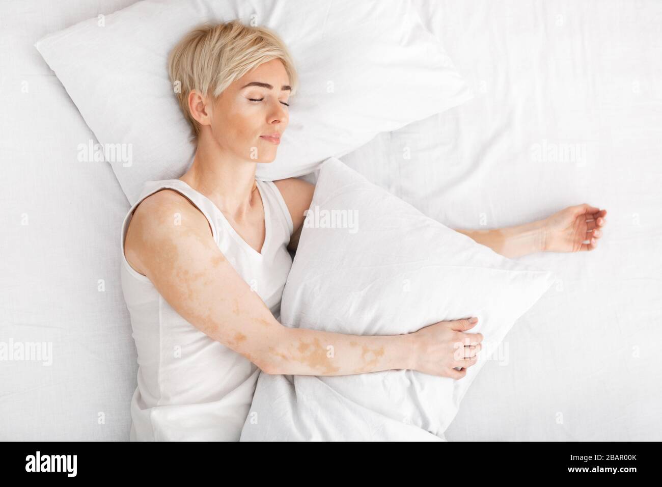 Middle aged lady sleeping in white bed, stay at home Stock Photo