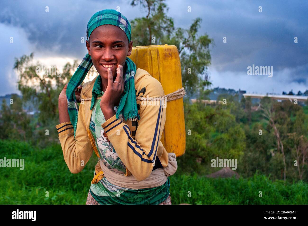 A girl carries a can of water across a field in Lalibela, Amhara region, Northern Ethiopia Stock Photo