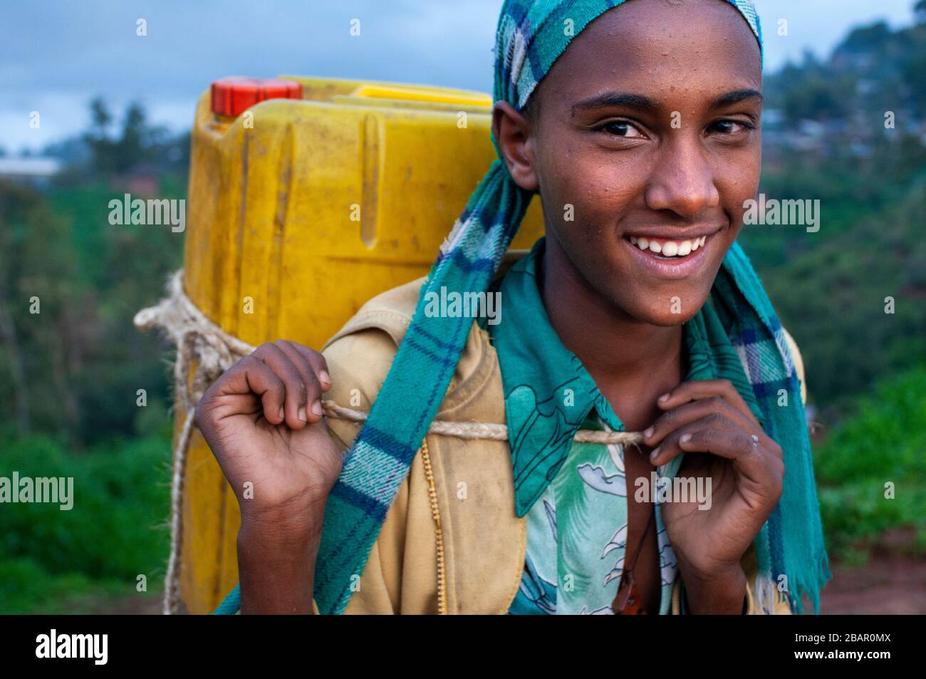 A girl carries a can of water across a field in Lalibela, Amhara region, Northern Ethiopia Stock Photo
