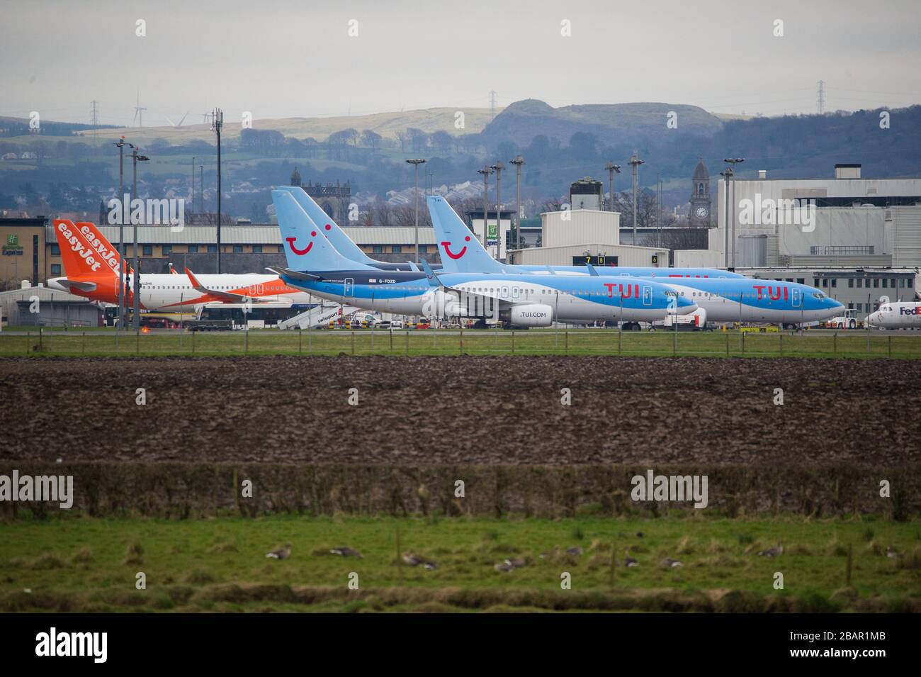 Glasgow, UK. 27 March 2020. Pictured: Grounded TUI planes at Glasgow Airport.  The Coronavirus Pandemic has been responsible for the UK shutdown aviation bringing Glasgow Airport to look more like a ghost town. Credit: Colin Fisher/Alamy Live News. Stock Photo