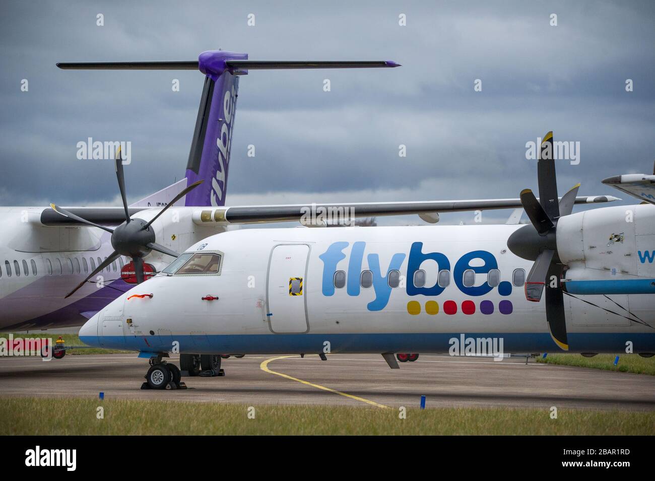 Glasgow, UK. 27 March 2020. Pictured: Grounded Flybe De Havilland Canada Dash 8 Q400 Aircraft seen parked up on the tarmac by the Emergency Rendezvous point at Glasgow Airport.  The Coronavirus Pandemic has been responsible for the UK shutdown aviation bringing Glasgow Airport to look more like a ghost town. Credit: Colin Fisher/Alamy Live News. Stock Photo